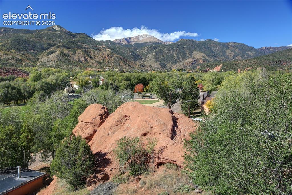 Image 11 of 26: Expansive mountain landscape featuring prominent red rock formations, matur