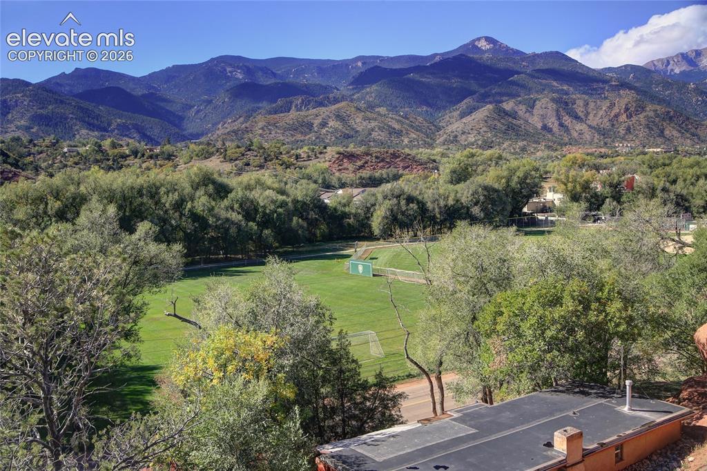 Image 14 of 26: Expansive mountain range backdrop featuring mature trees and a manicured gr