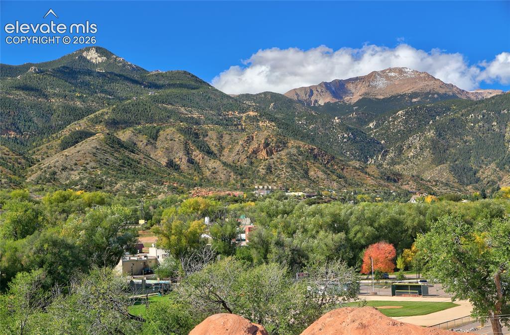 Image 2 of 26: Expansive mountain range backdrop, mature deciduous trees, and natural red 