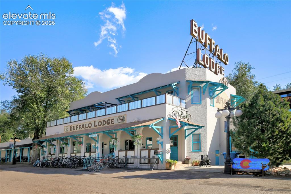 Image 22 of 26: Two-story stucco exterior featuring a covered front porch, teal structural