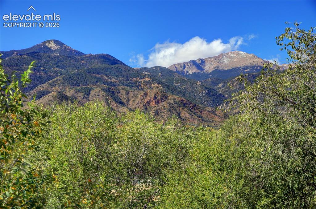 Image 8 of 26: Mountainous backdrop featuring prominent rocky peaks, dense evergreen fores