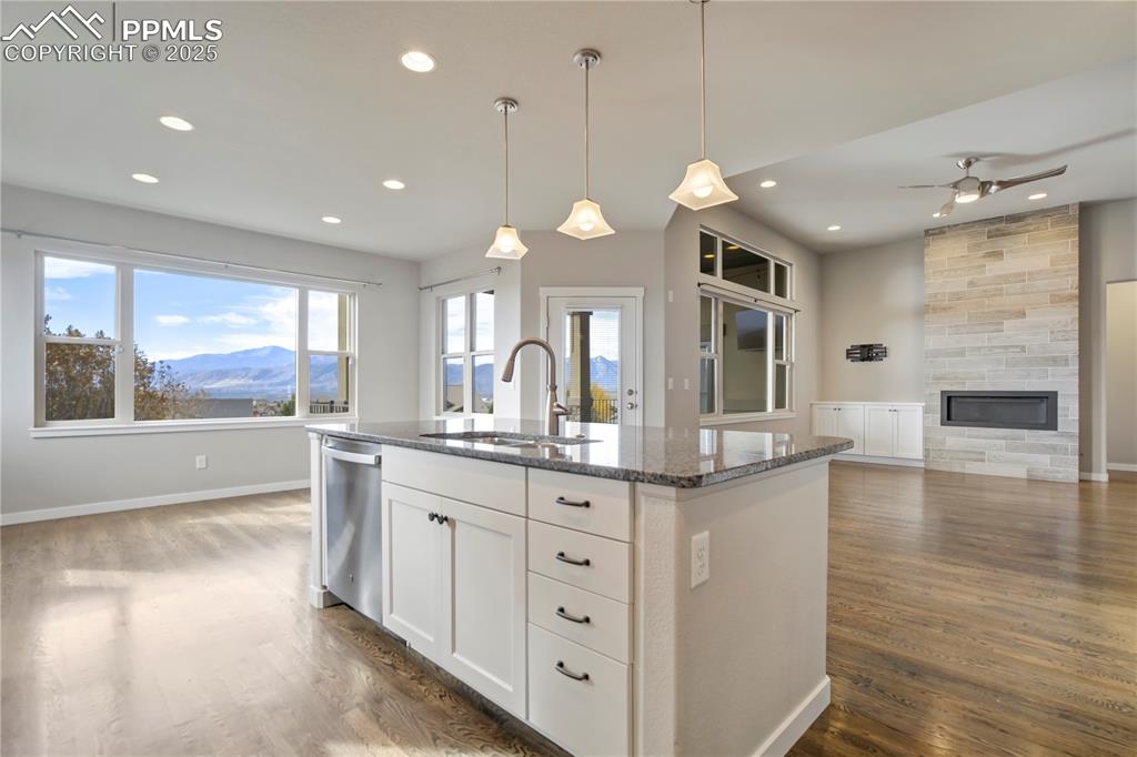 Image 13 of 50: Kitchen with a mountain view, dark stone countertops, pendant lighting, whi