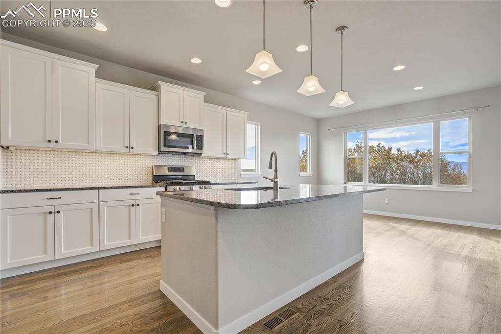 Image 14 of 50: Kitchen featuring tasteful backsplash, dark stone counters, a kitchen islan