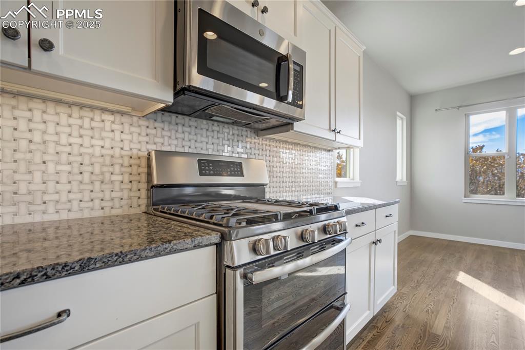 Image 15 of 50: Kitchen featuring stainless steel appliances, decorative backsplash, white 