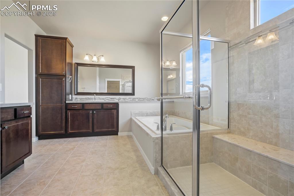 Image 22 of 50: Primary Bathroom with a garden tub, vanity, a stall shower, light tile patt