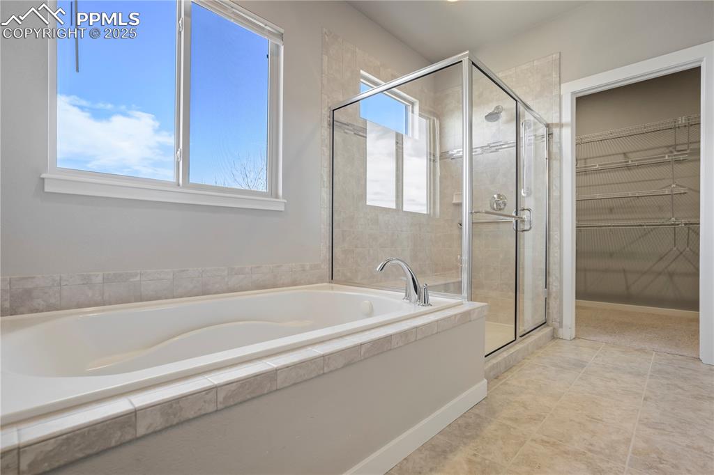 Image 24 of 50: Primary Bathroom with a shower stall, a garden tub, a spacious closet, and 