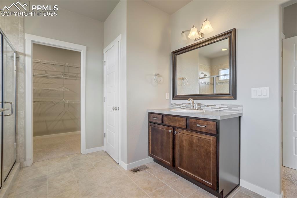 Image 25 of 50: Primary Full bath with vanity, light tile patterned flooring, a stall showe