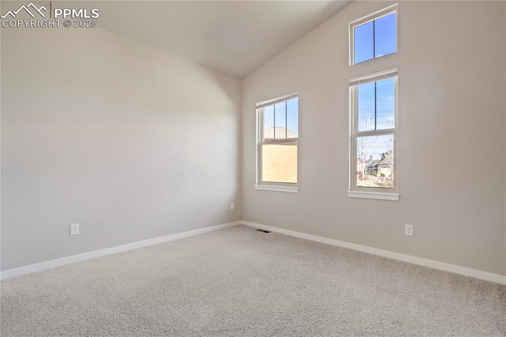Image 31 of 50: Carpeted room with lofted ceiling and baseboards