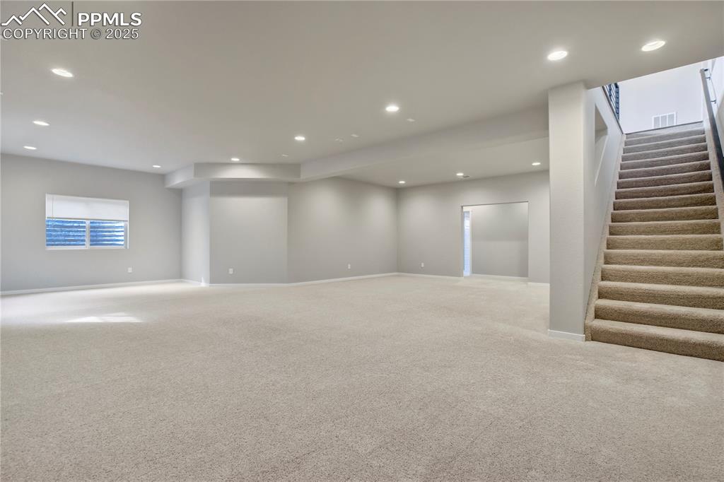 Image 34 of 50: Below grade area with carpet floors, recessed lighting, and stairs