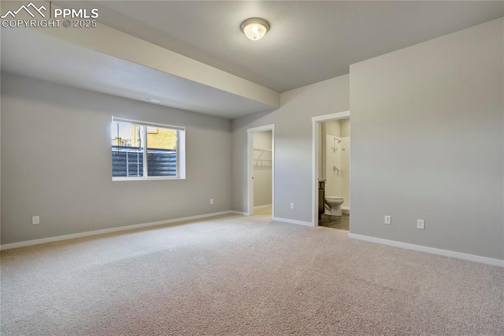 Image 39 of 50:  bedroom with a spacious closet, light colored carpet, and connected bathro