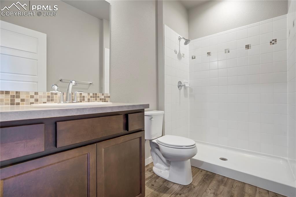 Image 40 of 50: private Full bathroom featuring vanity, dark wood finished floors, decorati