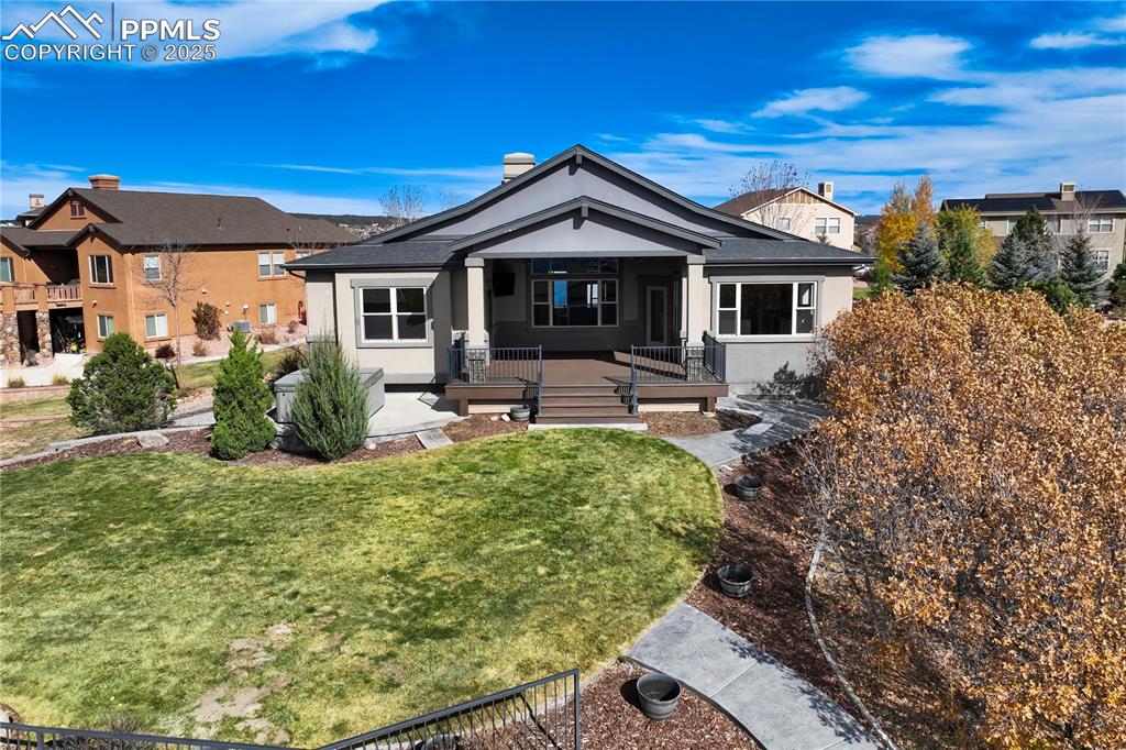 Image 49 of 50: View of rear facade featuring covered porch, stucco siding, and a back yard