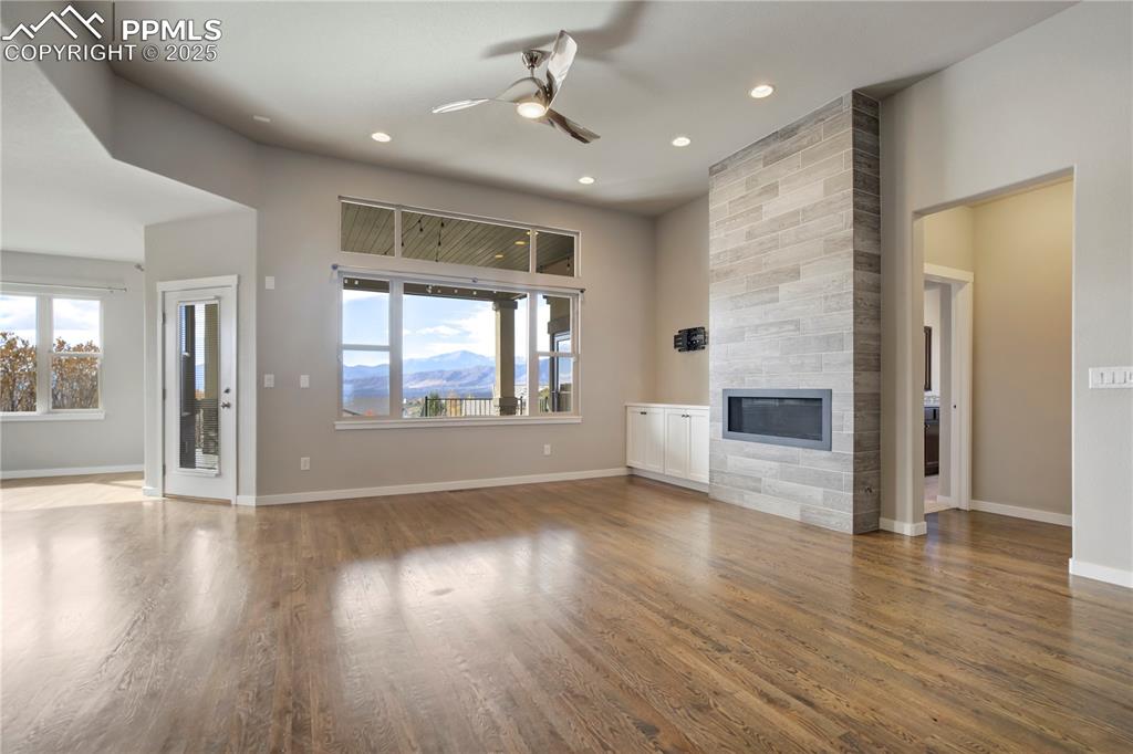 Image 5 of 50: living room with ceiling fan, a large fireplace, wood finished floors, heal