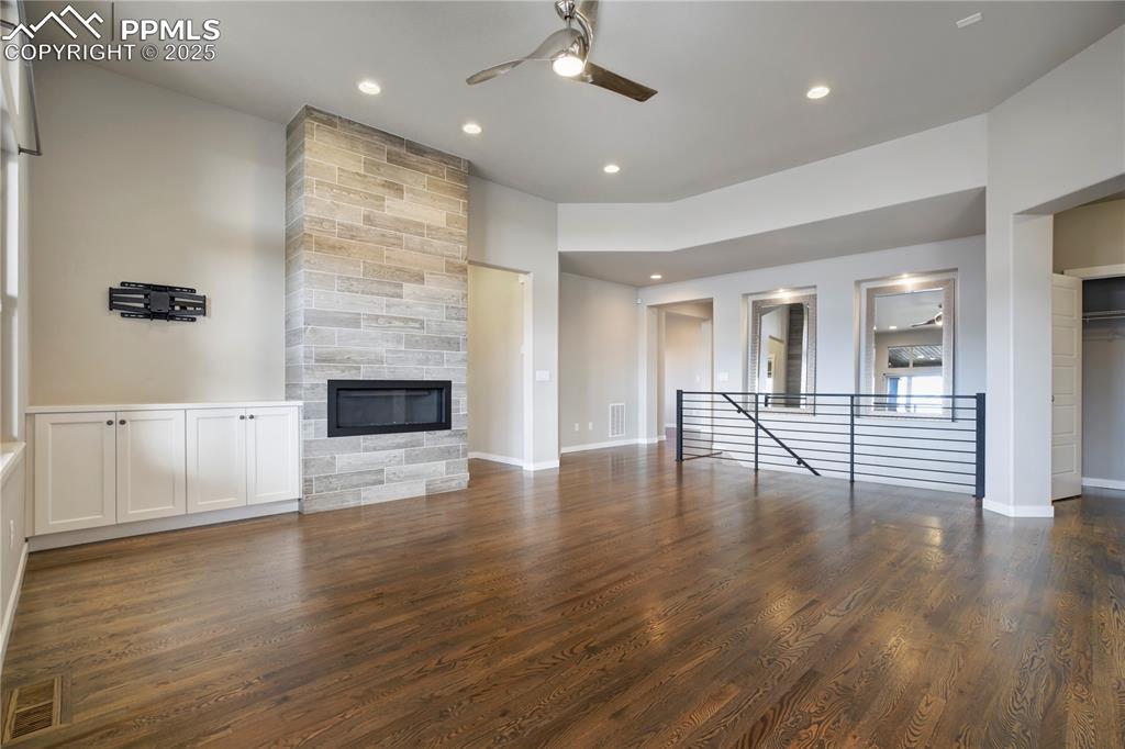 Image 8 of 50: living room with a ceiling fan, dark wood-style floors, a large fireplace, 