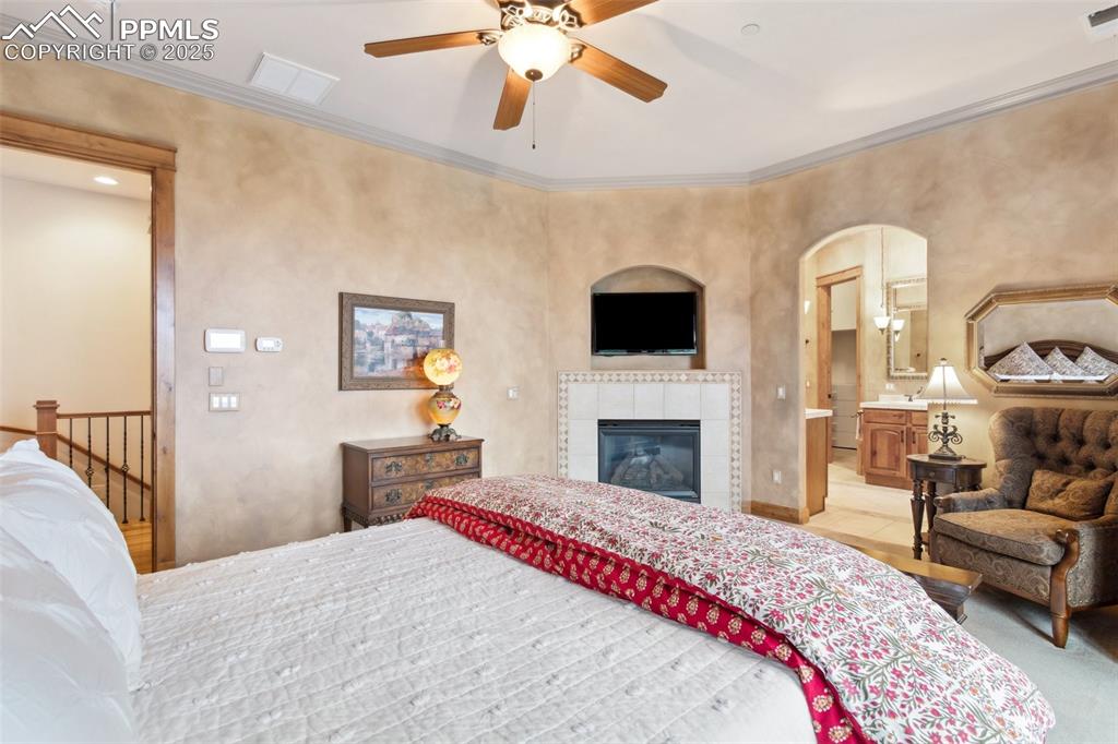 Image 20 of 49: Primary Bedroom with gas fireplace, TV and mount, and archway into the 5-Pi