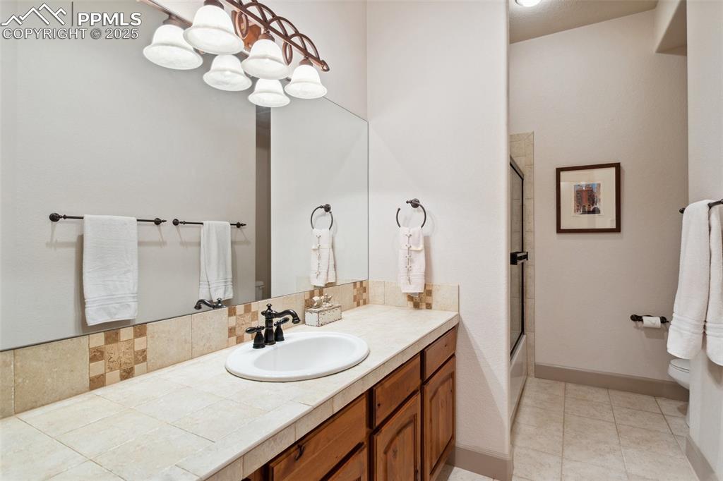 Image 31 of 49: Basement Shower Bathroom with extended vanity, mirror, and enclosed tiled s