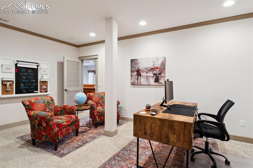 Image 35 of 49: Basement Stufy with neutral carpet and Pottery Barn wall organizer that sta