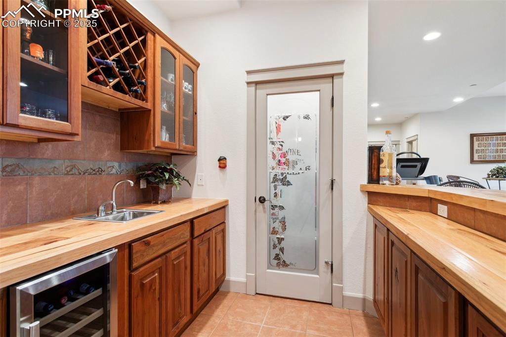 Image 41 of 49: Basement wet bar, with tile countertops, upper and lower cabinets, built-in