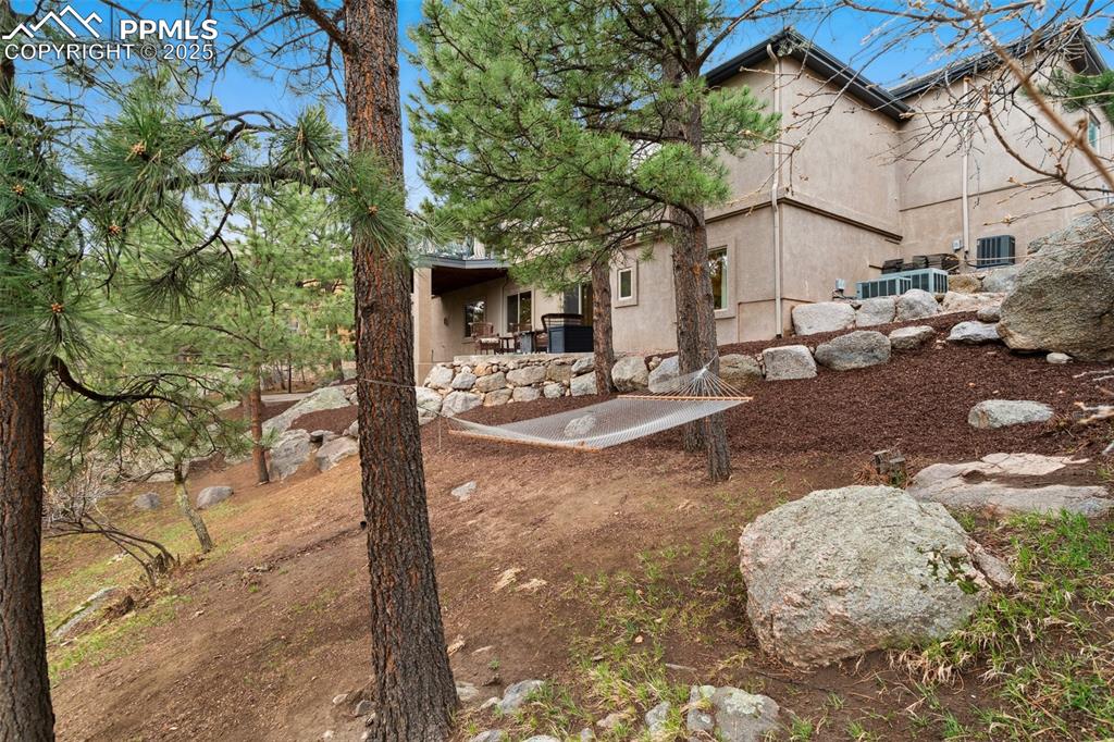 Image 48 of 49: Sloped backyard with mature trees and several outdoor living areas to enjoy