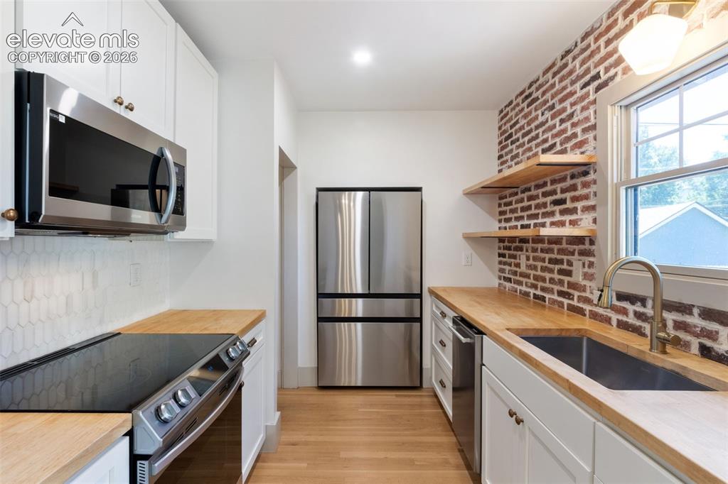Image 2 of 33: Shaker style cabinets, brick wall, modern kitchen, solid hardwood floors