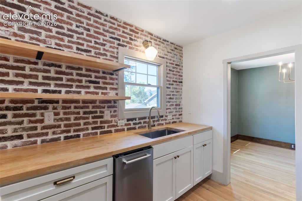 Image 3 of 33: Shaker style cabinets, brick wall, modern kitchen, solid hardwood floors
