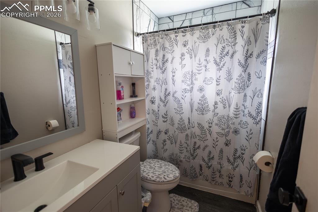 Image 10 of 11: Bathroom featuring vanity, shower / bath combo, and dark wood-style floorin