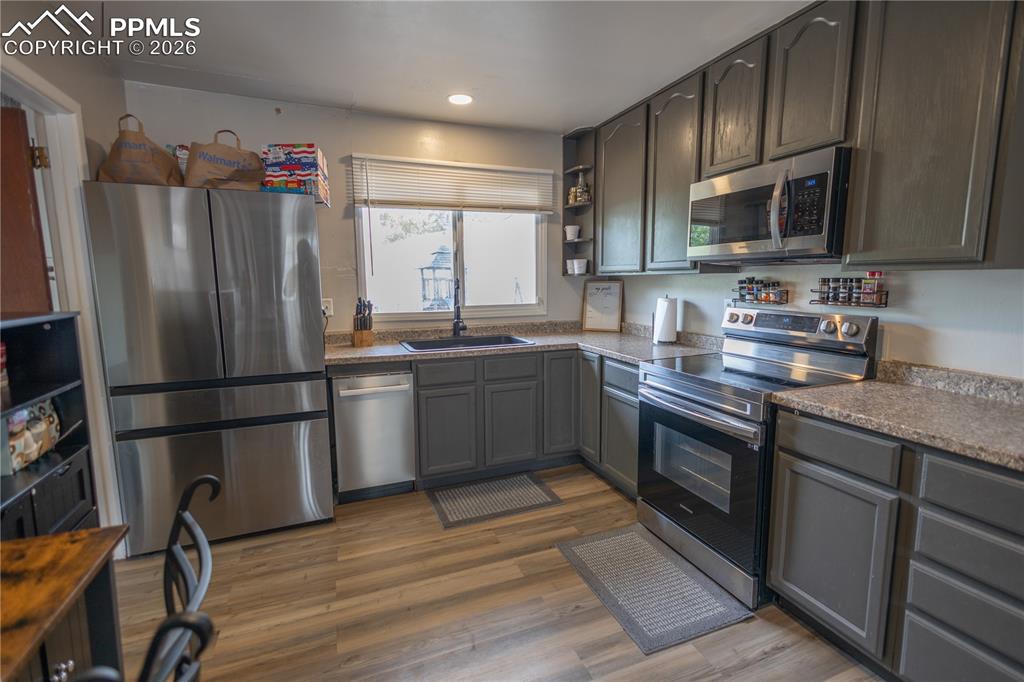Image 5 of 11: Kitchen featuring stainless steel appliances, dark countertops, open shelve