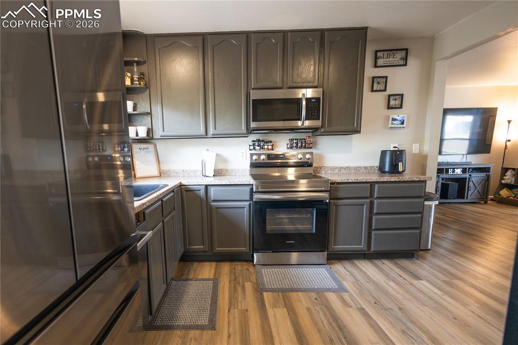 Image 6 of 11: Kitchen featuring stainless steel appliances, light wood-type flooring, ope