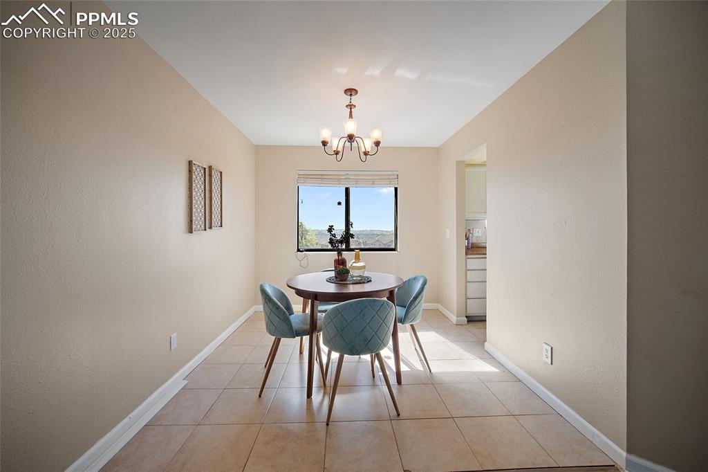 Image 10 of 45: Dining room with light tile patterned floors, a chandelier, and a textured