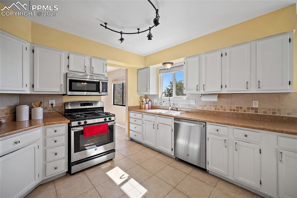 Image 13 of 45: Kitchen featuring appliances with stainless steel finishes, white cabinetry