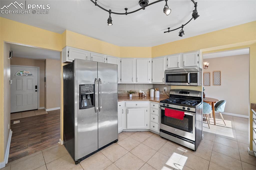 Image 14 of 45: Kitchen with appliances with stainless steel finishes, white cabinets, ligh