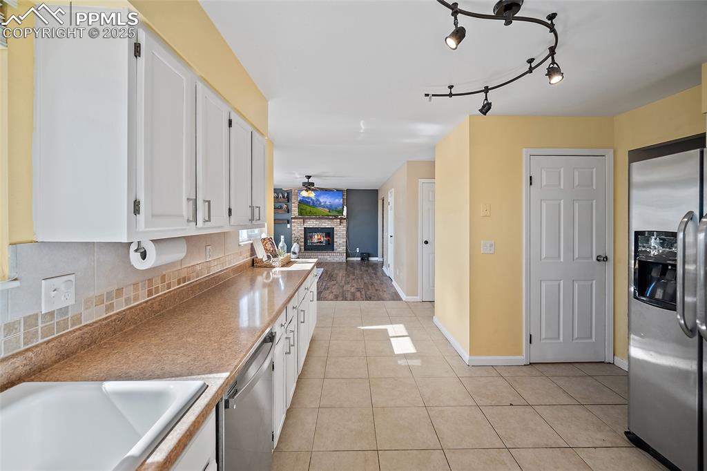Image 15 of 45: Kitchen featuring stainless steel appliances, a fireplace, light tile patte