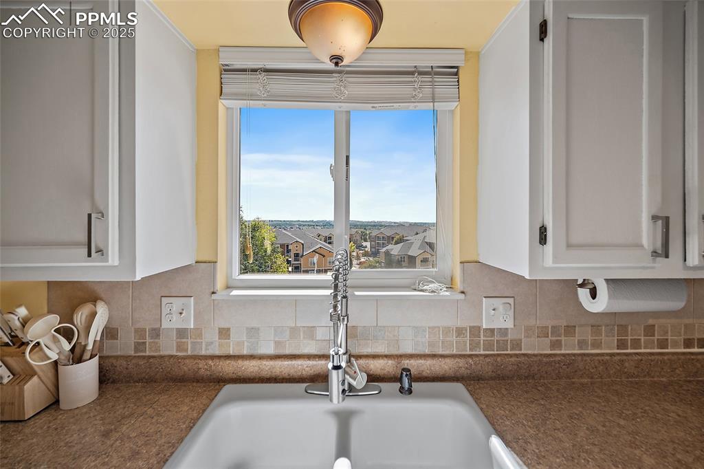 Image 16 of 45: Kitchen with dark countertops, backsplash, and white cabinets