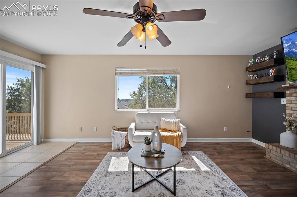 Image 18 of 45: Sitting room featuring dark wood-style floors, a ceiling fan, and a firepla