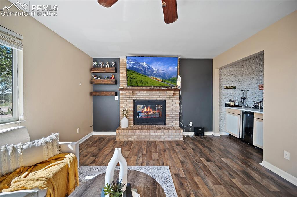 Image 20 of 45: Living room featuring dark wood-type flooring, a fireplace, a ceiling fan,