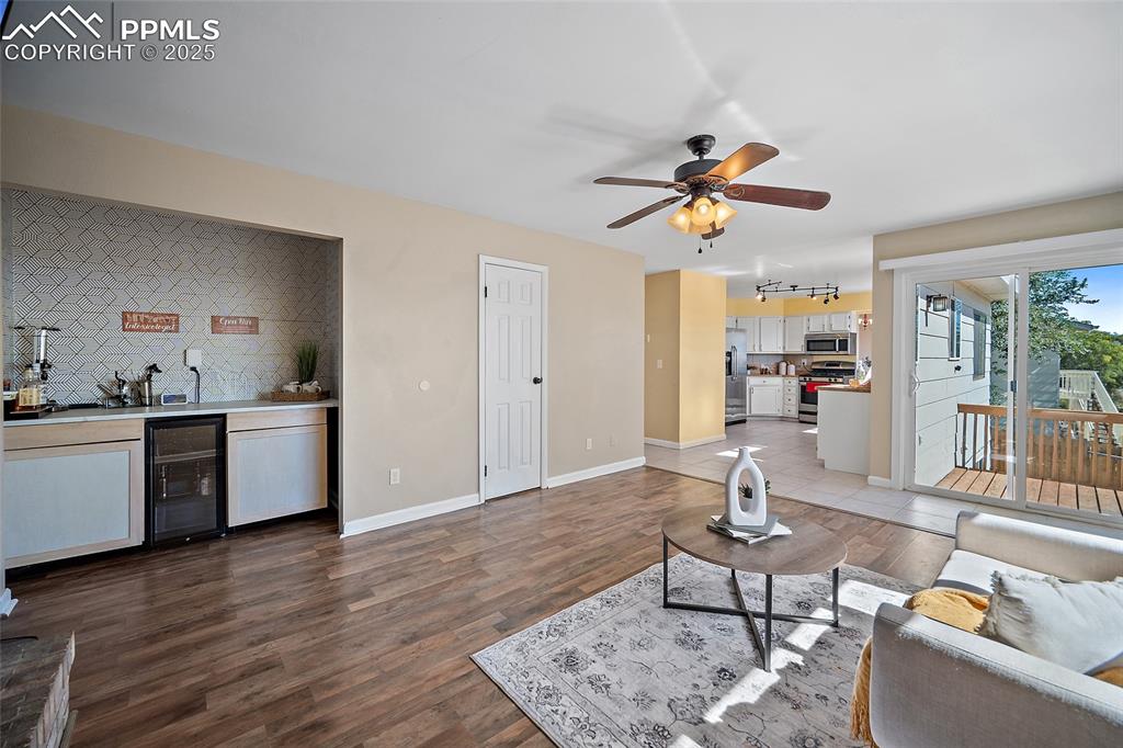 Image 21 of 45: Living area with wine cooler, dark wood-style floors, and ceiling fan