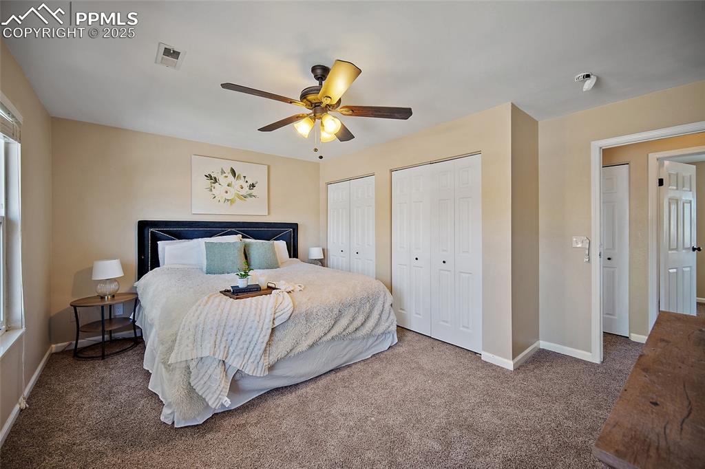 Image 24 of 45: Carpeted bedroom featuring two closets and ceiling fan