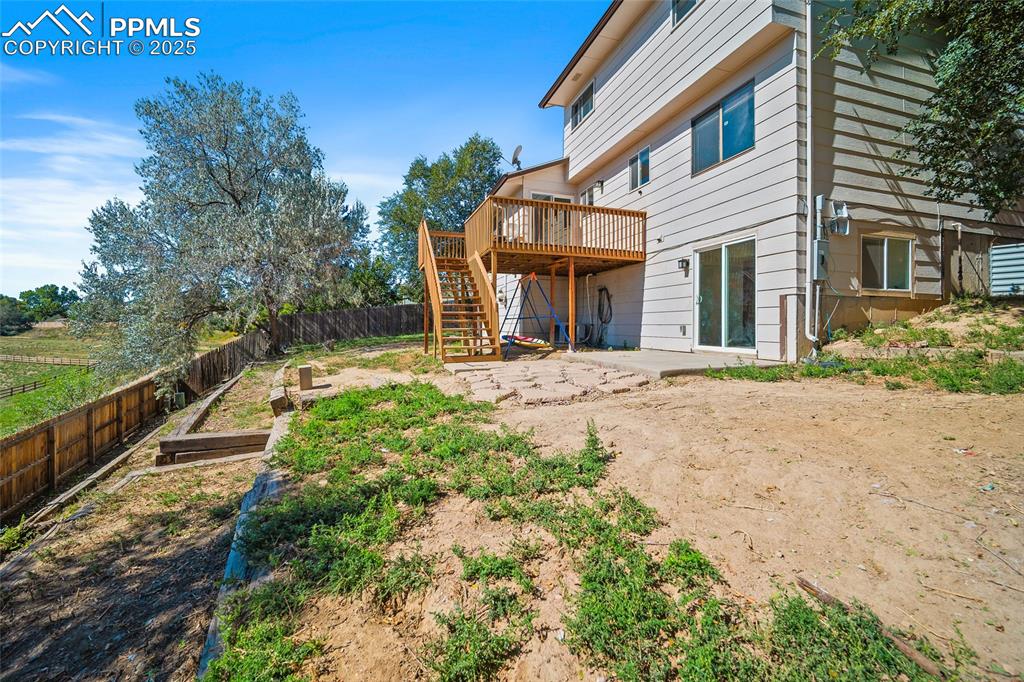 Image 38 of 45: Back of house featuring a patio area, stairs, a garden, a wooden deck, and