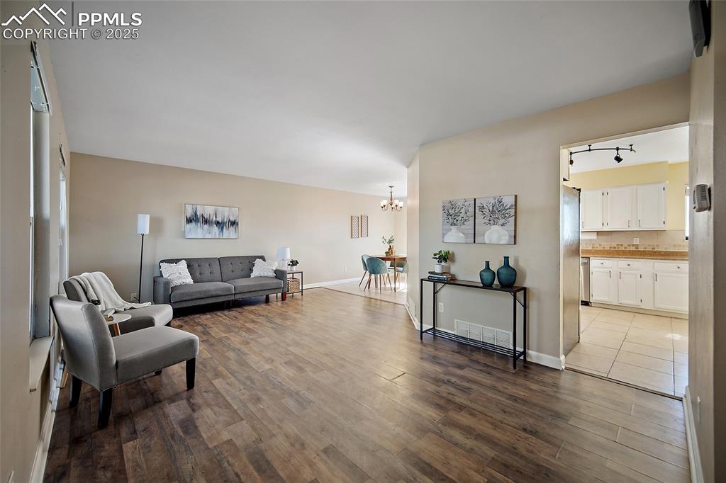 Image 5 of 45: Living room with dark wood-type flooring and a chandelier