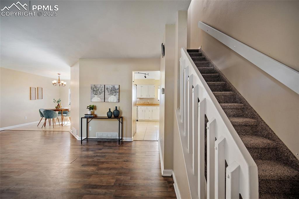 Image 6 of 45: Stairway featuring wood finished floors and a chandelier