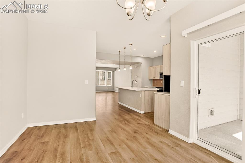 Image 12 of 38: Dining room has chandelier matching kitchen pendant lighting