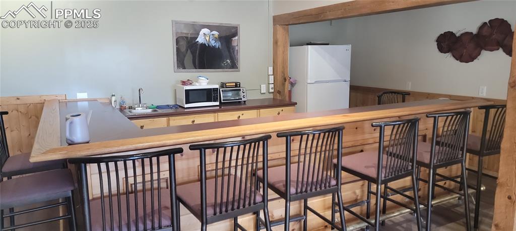 Image 12 of 23: Indoor wet bar featuring white appliances