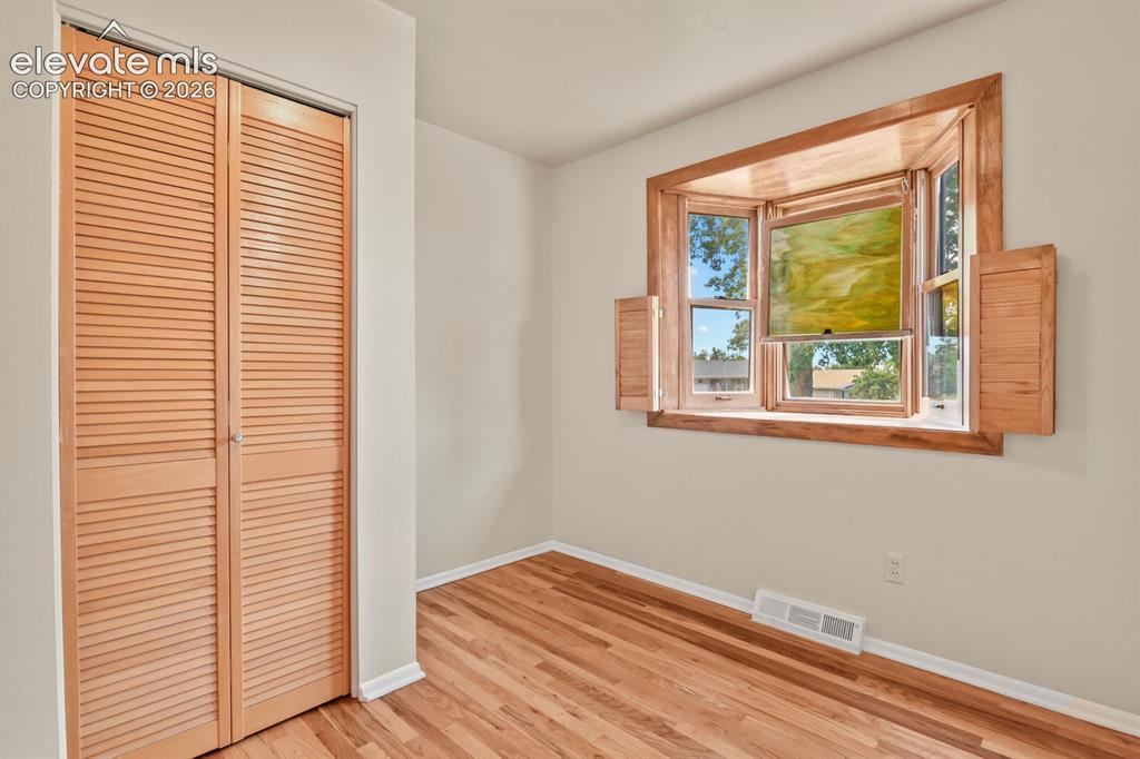 Image 20 of 45: Secondary bedroom on main floor looking towards the bay window.