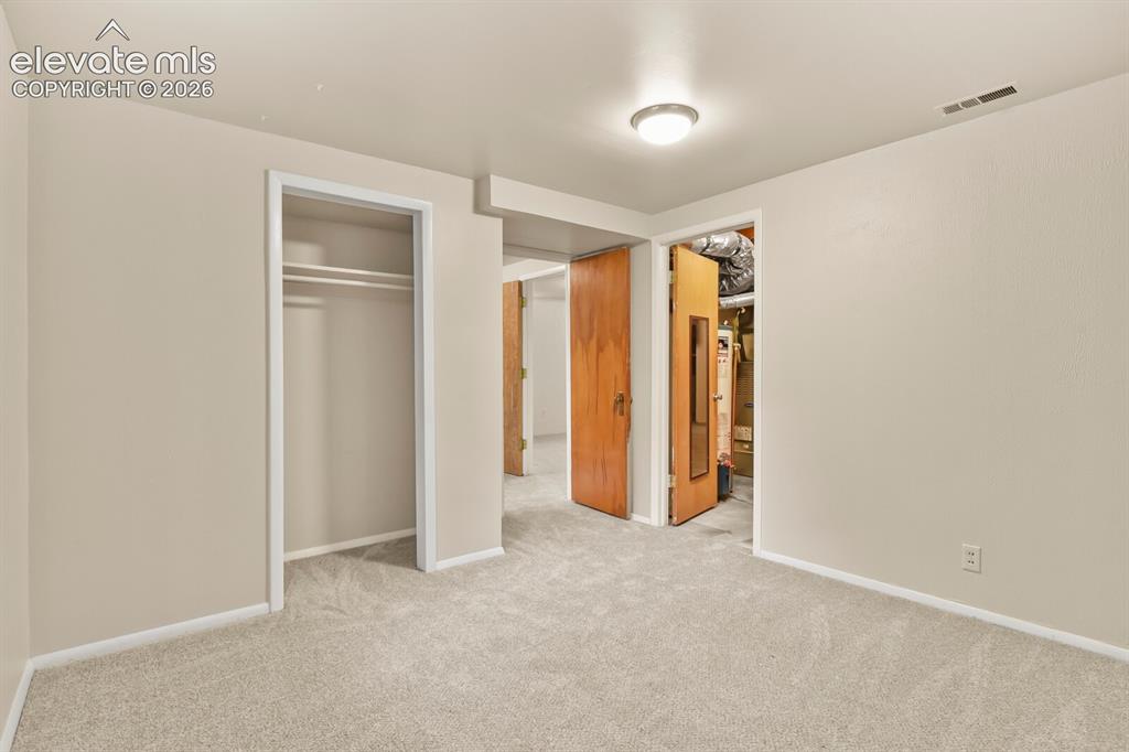 Image 32 of 45: Front-corner basement bedroom looking towards door to laundry room and livi