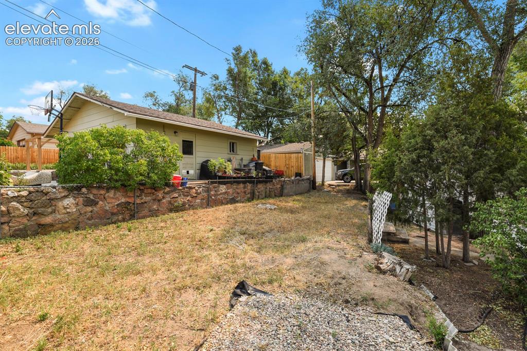 Image 45 of 45: Section of back yard behind workshop looking at back fence/wall.