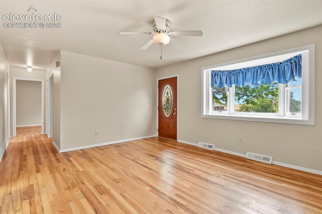 Image 7 of 45: Far corner of living room looking down hallway and toward front door & bay