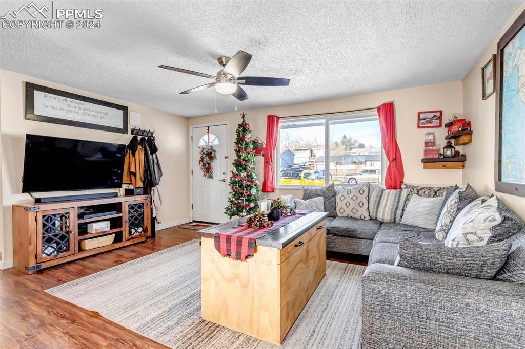 Image 5 of 37: Living room featuring ceiling fan, a textured ceiling, and hardwood / wood-