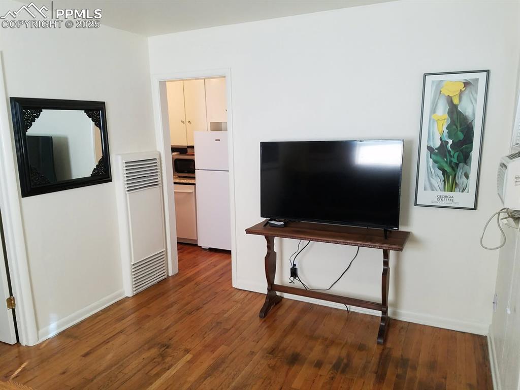 Image 15 of 25: Living area featuring a heating unit, wood finished floors, and baseboards