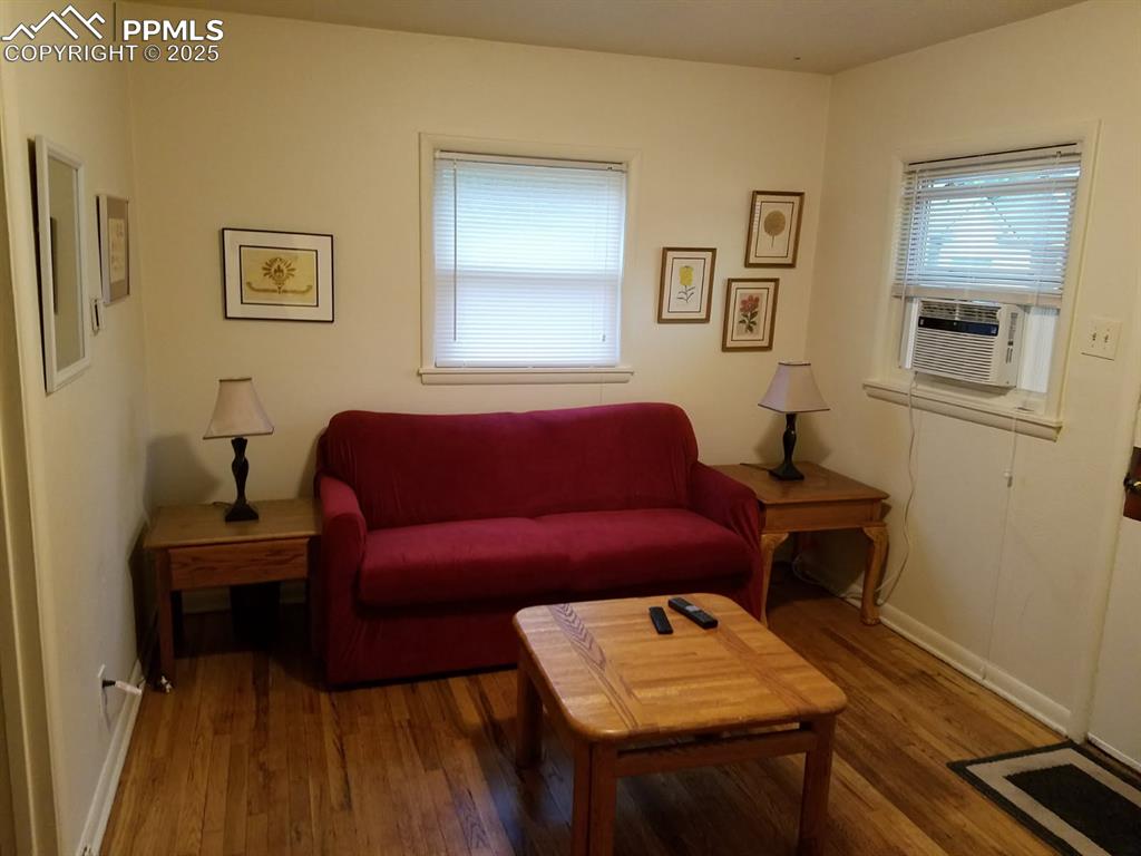 Image 16 of 25: Living area with wood finished floors, cooling unit, and baseboards