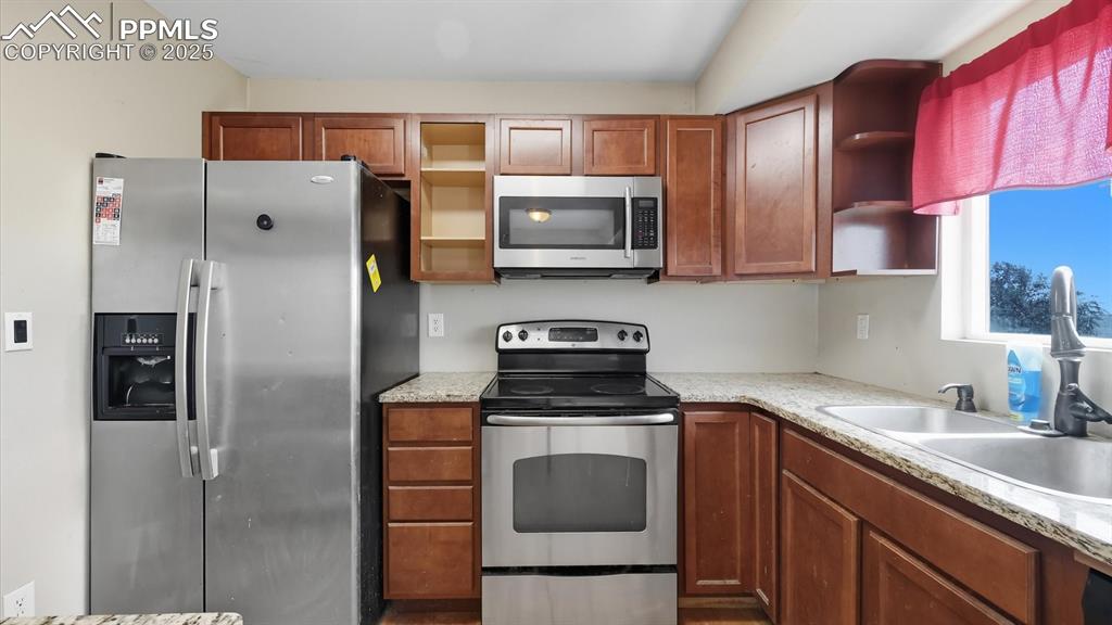 Image 12 of 34: Appliances include a range oven, microwave, dishwasher, and side by side re